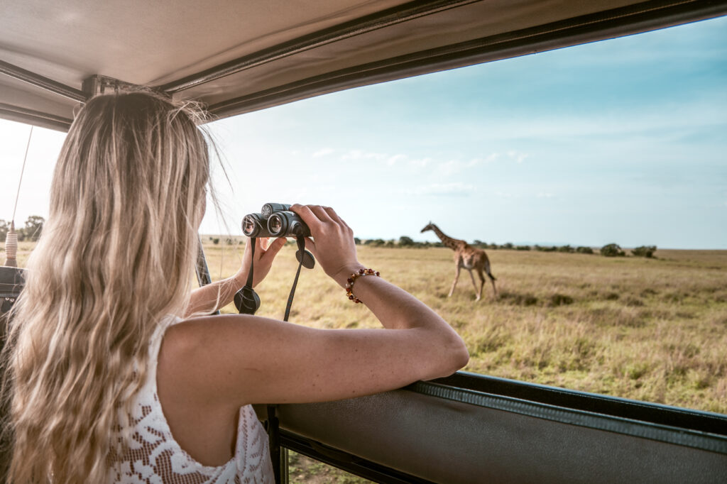 turista osserva giraffa dalla jeep nel masai mara